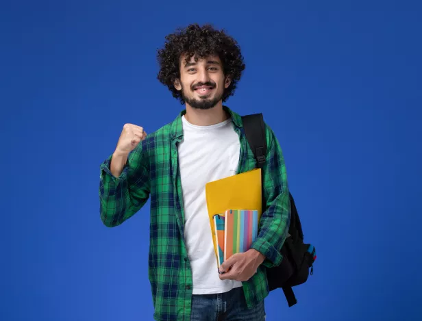 front-view-male-student-wearing-black-backpack-holding-copybooks-files-blue-wall