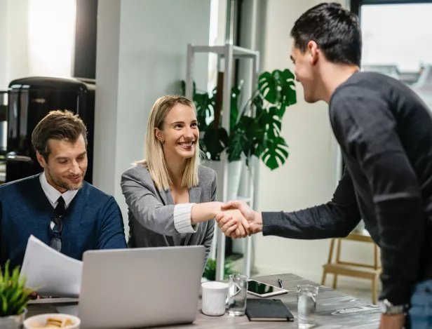 two-financial-advisors-having-meeting-with-young-man-at-home-female-advisor-is-shaking-hands-with-client